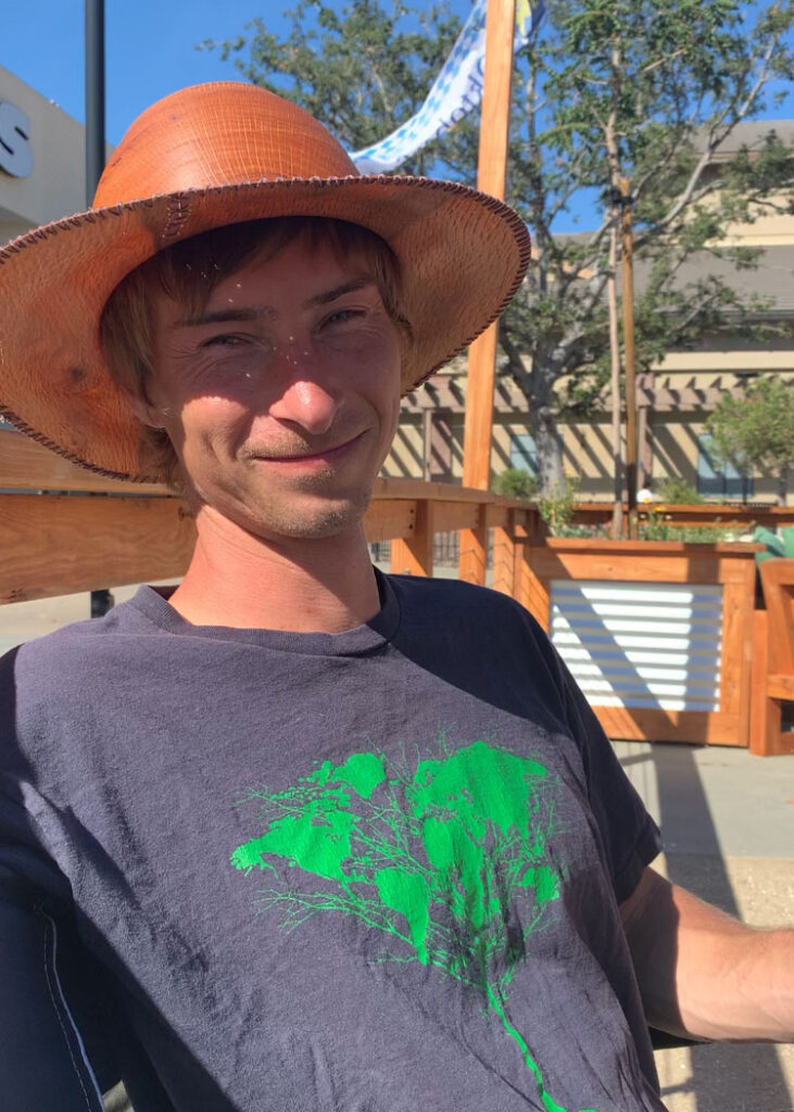 Luke Garrison, woodturner wearing a wooden hat sitting in the sun